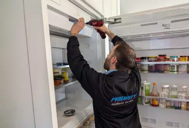 Priority Appliance Service technician repairing a refrigerator